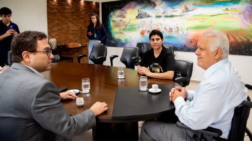 A meeting at a conference table with three individuals engaged in conversation, surrounded by a colorful mural.